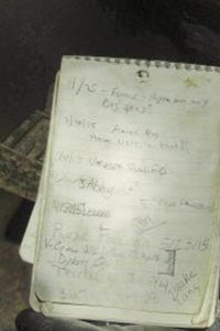 An aged flip notebook showing previous registers in the cave.