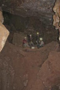 A wide view from inside the cave, people standing on a ridge.