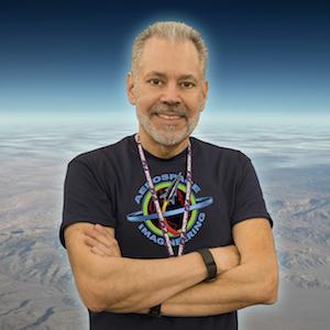 Aldo Spadoni casually stands with arms crossed in front of a planet background.