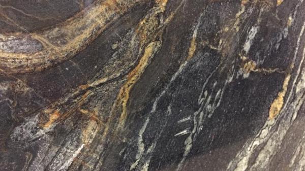 A close up of a slab of rock showing layers of light to dark grey, black and tan.