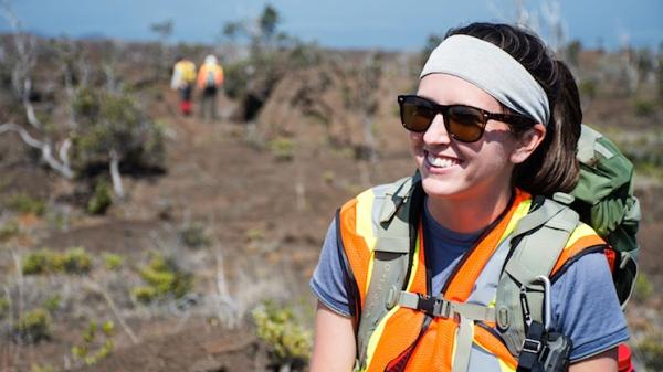 Kelsey is a high desert landscape wearing a backpack and reflective gear in Hawaii.