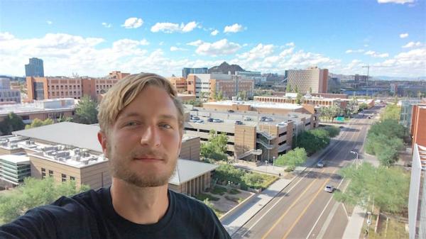 Mark stands from a balcony with the ASU campus and A mountain in the background.
